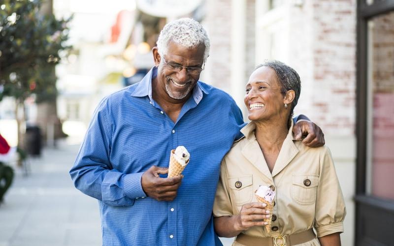 Close to the center of everything older couple walks down city sidewalk while holding ice cream cones